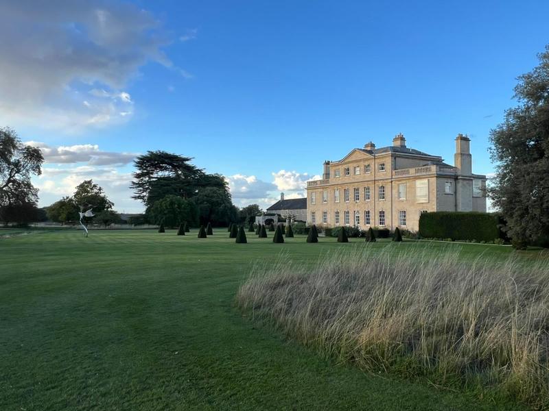 Country house beyond a mown lawn and meadow grass, cared for by Haynes Horticulture