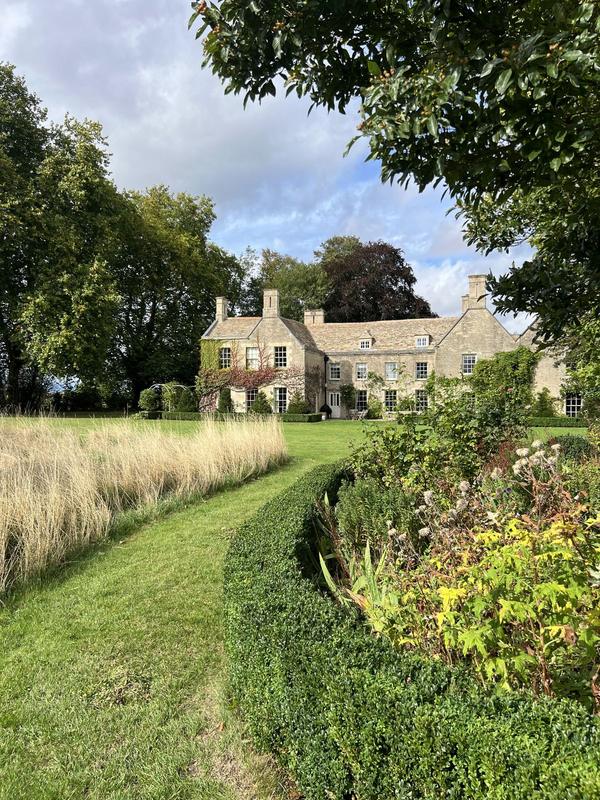 Lawn path between planted borders leading to a stone cottage