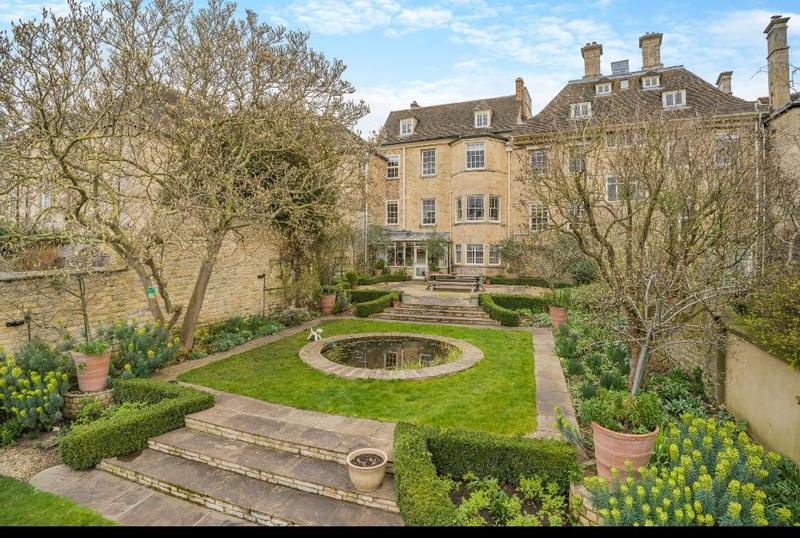 Formal garden with clipped hedging and a central feature below a stone house